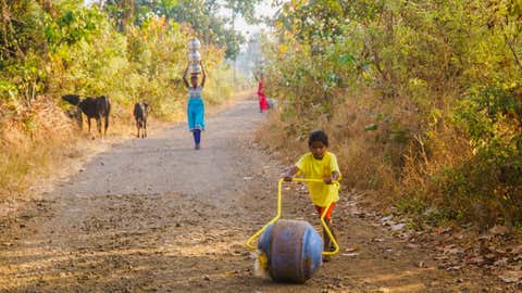 Tribal women, trudging uphill to their village with drinking water from Vanvadi open well, with an innovative rotatable water container. (Sanjiv Valson and Rishi Gangoli)