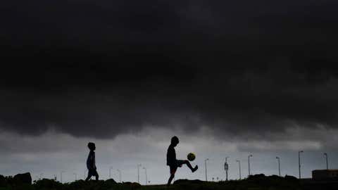 Children play football under dark monsoon clouds. (SL Shanth Kumar/TOI, BCCL, Mumbai)