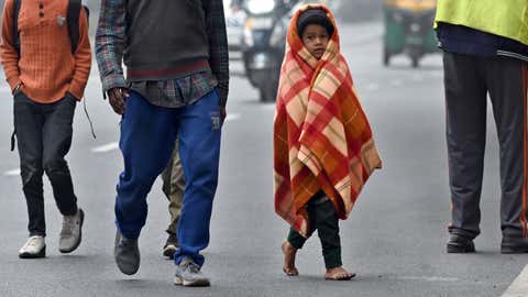 A child wearing a quilt walks barefoot on a cold winter morning in New Delhi. (Piyal Bhattacharjee/BCCL)