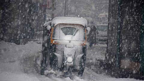 A vehicle moves slowly on a snow-covered road after a heavy snowfall.