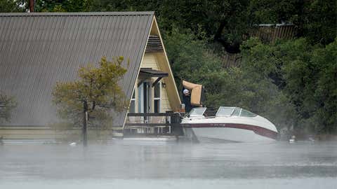 Loyd Reagan removes furniture from his house at Graveyard Point on Lake Travis on Wednesday, Oct. 17, 2018, in Austin, Texas. He used a boat to reach the second-floor deck of the house to save some of his belongings. (Jay Janner /Austin American-Statesman via AP)