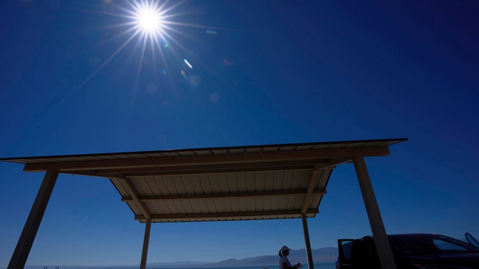 A woman packs up after resting in a shaded area alongside the Salton Sea as a record-breaking winter heat wave continues across the Southwest, Thursday, March 19, 2026, near North Shore, Calif. (AP Photo/Gregory Bull)