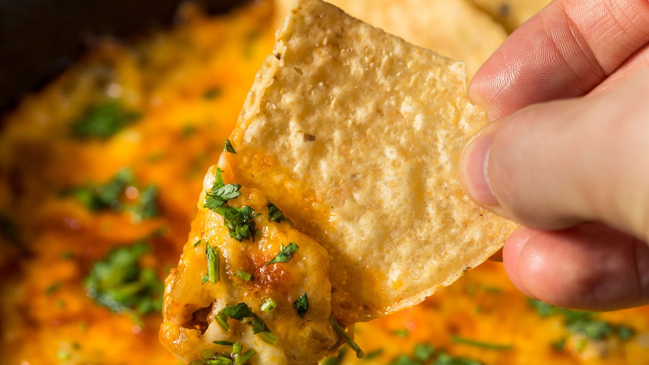 Person dipping tortilla chip into homemade Mexican Chorizo Queso Oaxaca Dip