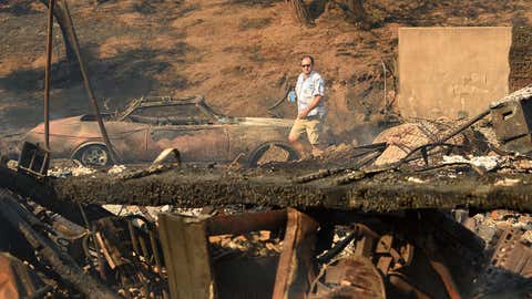 Eyad Jarjour (L) views his neighbor's burned residence after flames from the Saddleridge Fire tore through the region in Granada Hills, California on October 11, 2019. - The fire broke out late October 10 and has scorched some 4,600 acres (1,816 hectares), and forced mandatory evacuation orders for 12,700 homes. (Photo by Josh Edelson / AFP) (Photo by JOSH EDELSON/AFP via Getty Images)