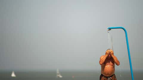 A man cools off in a beach shower during a hot summer day at the beach in De Haan, Belgium, Thursday, July 25, 2019 – the hottest day in the nation's history, with almost every weather station reporting all-time records. (AP Photo/Francisco Seco)