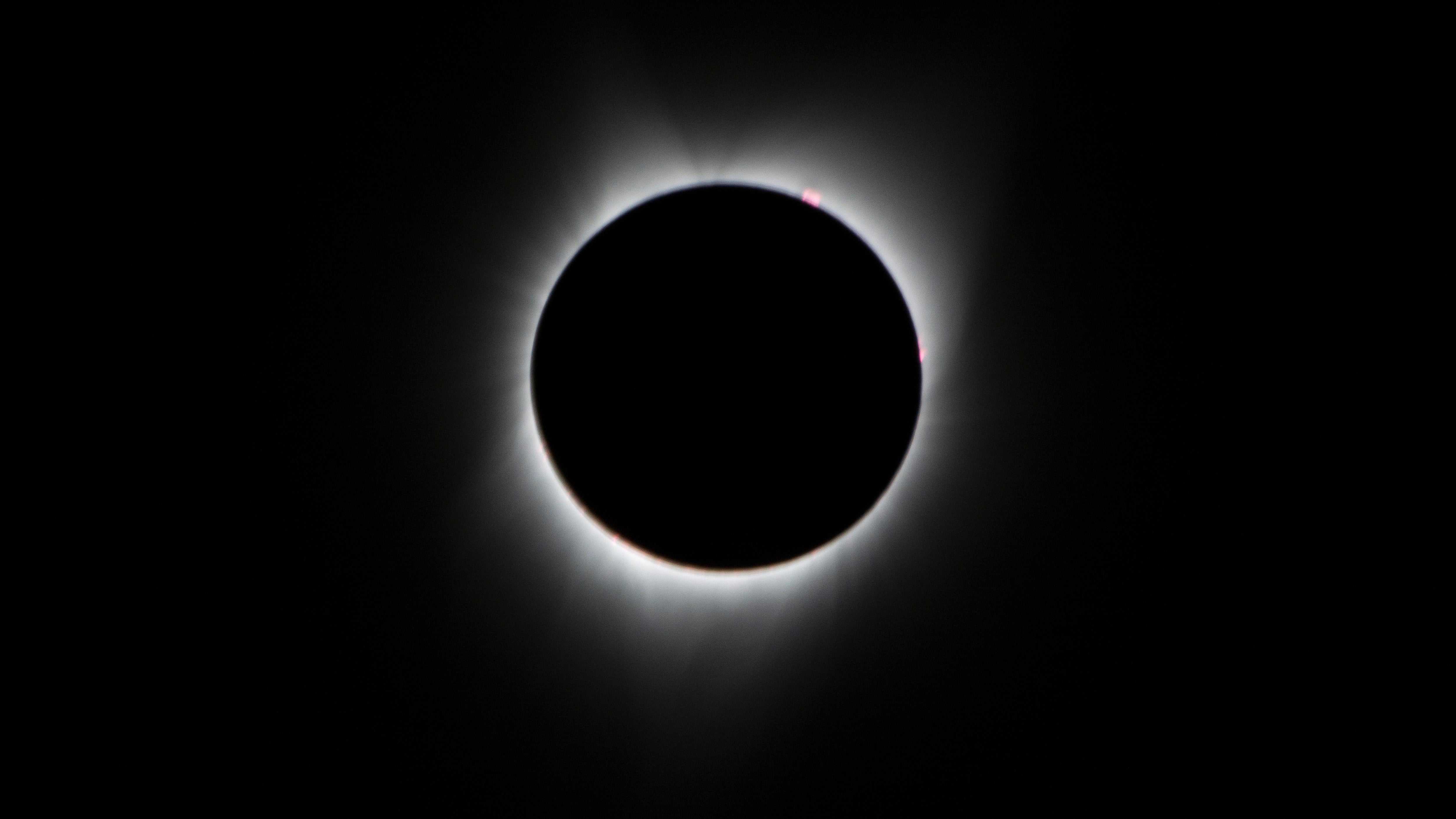 During the total solar eclipse, the Sun&rsquo;s corona, only visible during the total eclipse, is shown as a crown of white flares from the surface. The red spots called Bailey's beads occurs where the moon grazes by the Sun and the rugged lunar limb topography allows beads of sunlight to shine through in some areas as photographed from NASA Armstrong&rsquo;s Gulfstream III. Photo Credit: (NASA/Carla Thomas)