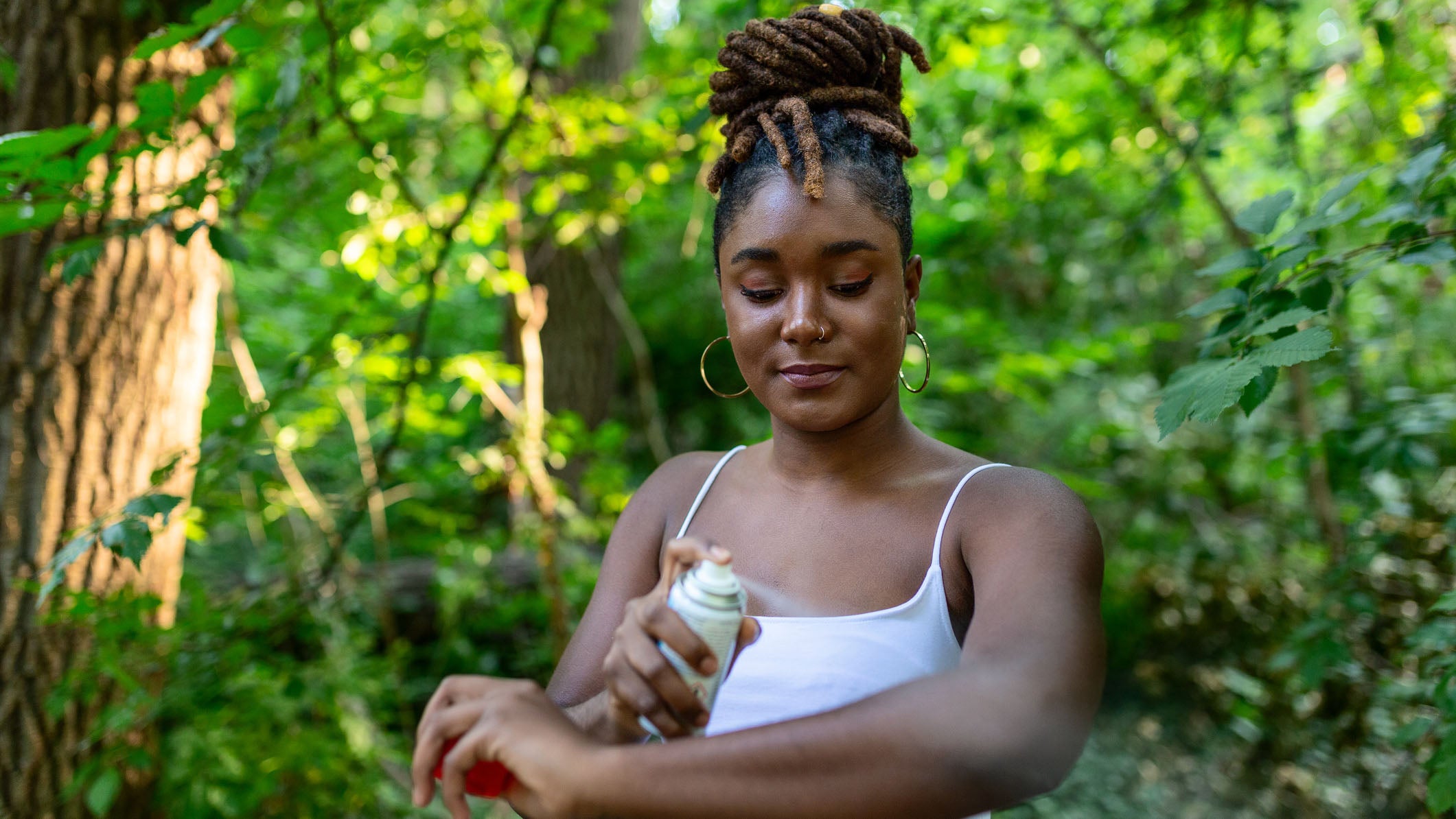 Woman applying insect repellent against mosquito and tick on her arms during hike in nature. Skin protection against insect bite