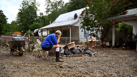 Teresa Reynolds sits exhausted as members of her community clean the debris from their flood ravaged homes at Ogden Hollar in Hindman, Ky., Saturday, July 30, 2022. (AP Photo/Timothy D. Easley)