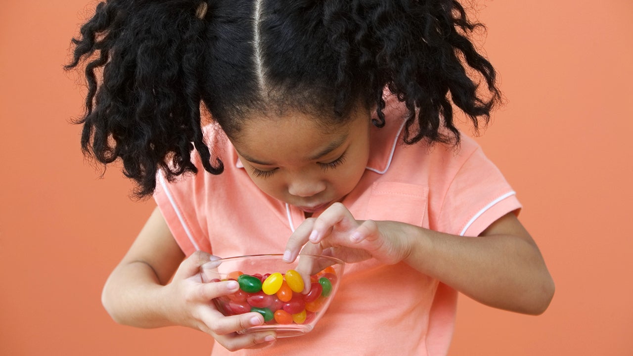 Asian girl with ponytails looking in bowl of candy
