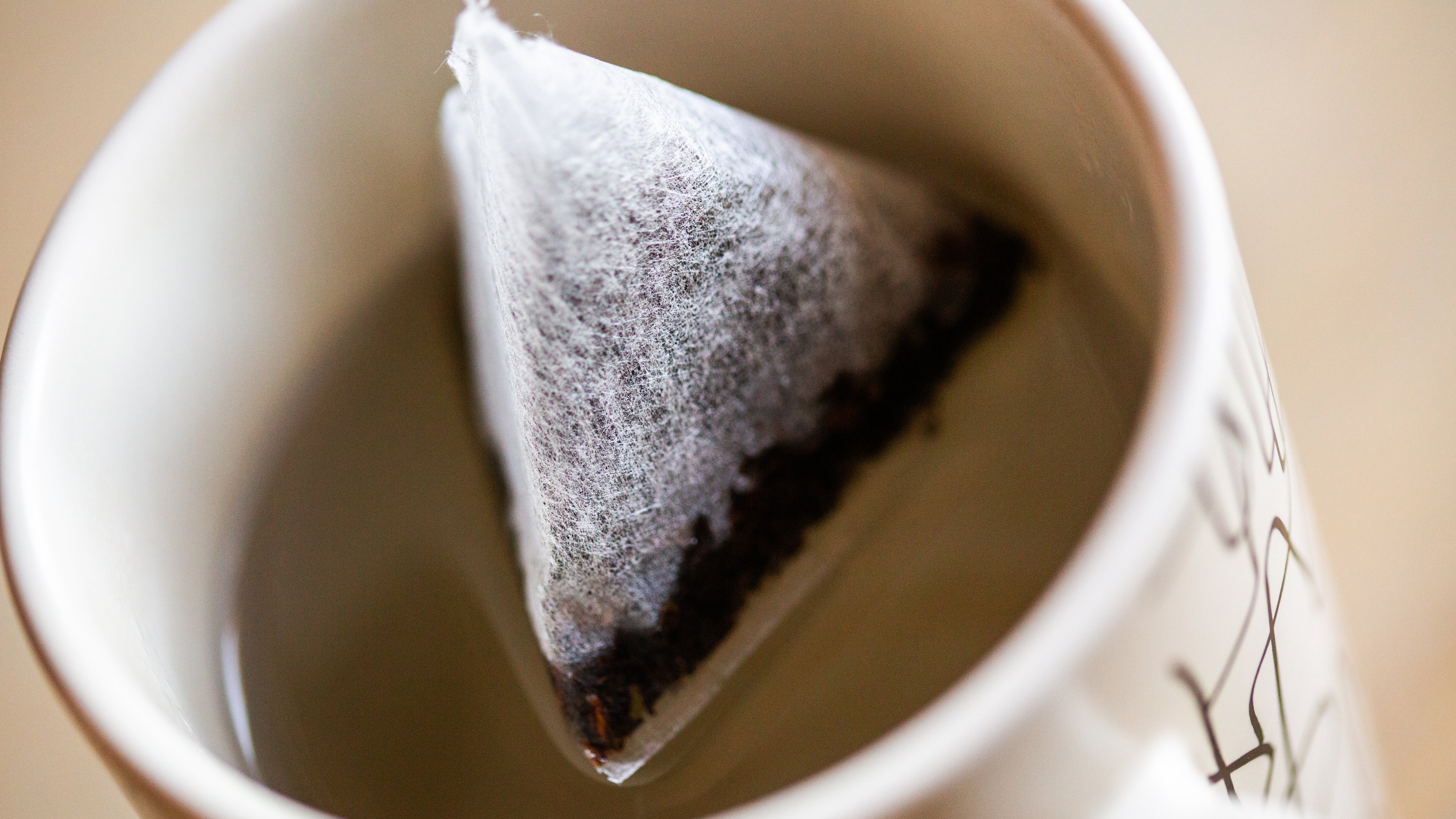 Un sachet de th&eacute; dans une tasse d'eau chaud pour un moment de d&eacute;tente. Le sachet de th&eacute; imbib&eacute; laisse &eacute;chapp&eacute;e les effluves agr&eacute;ables.