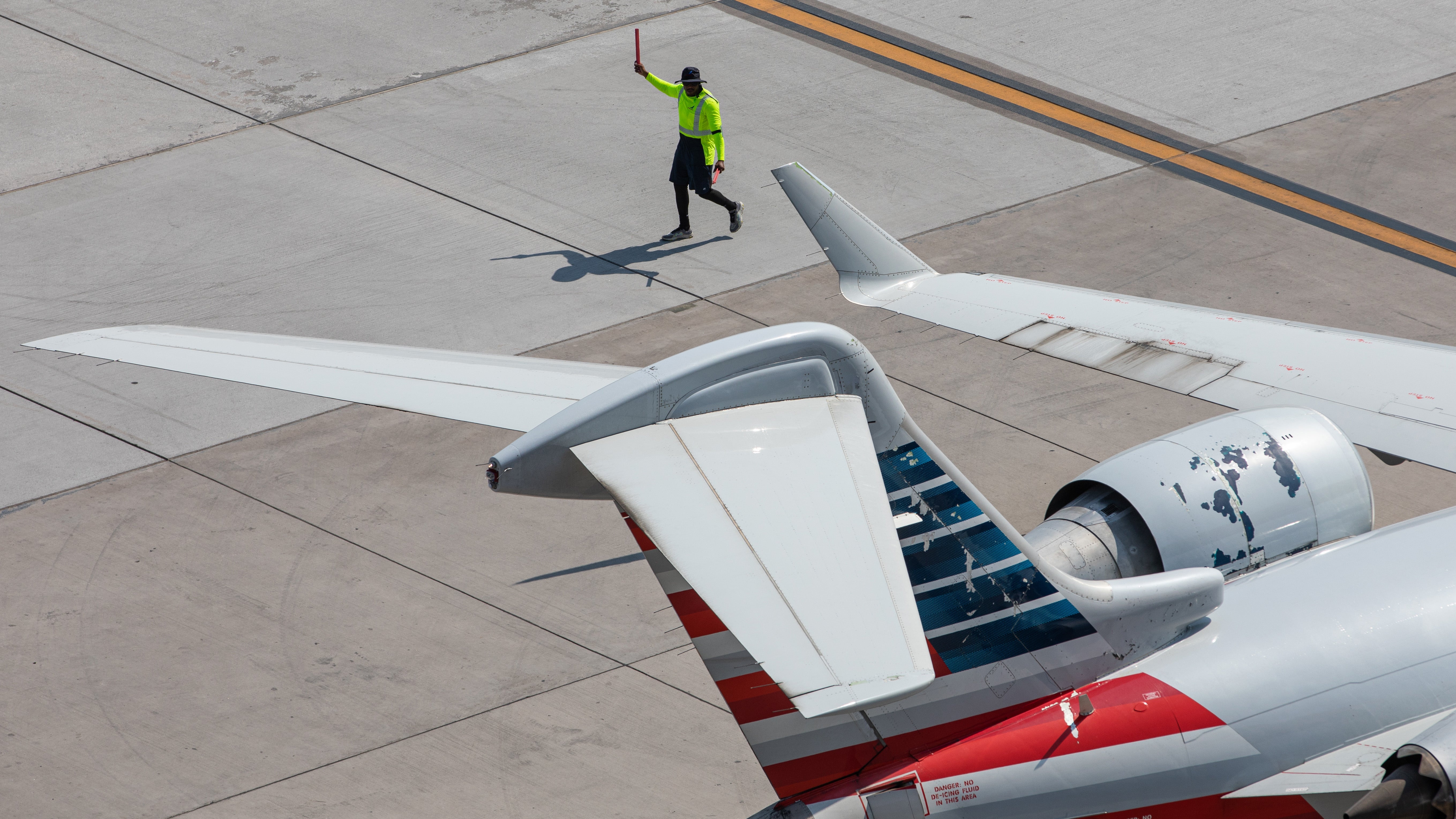 A man walks beside the tail of an airplane