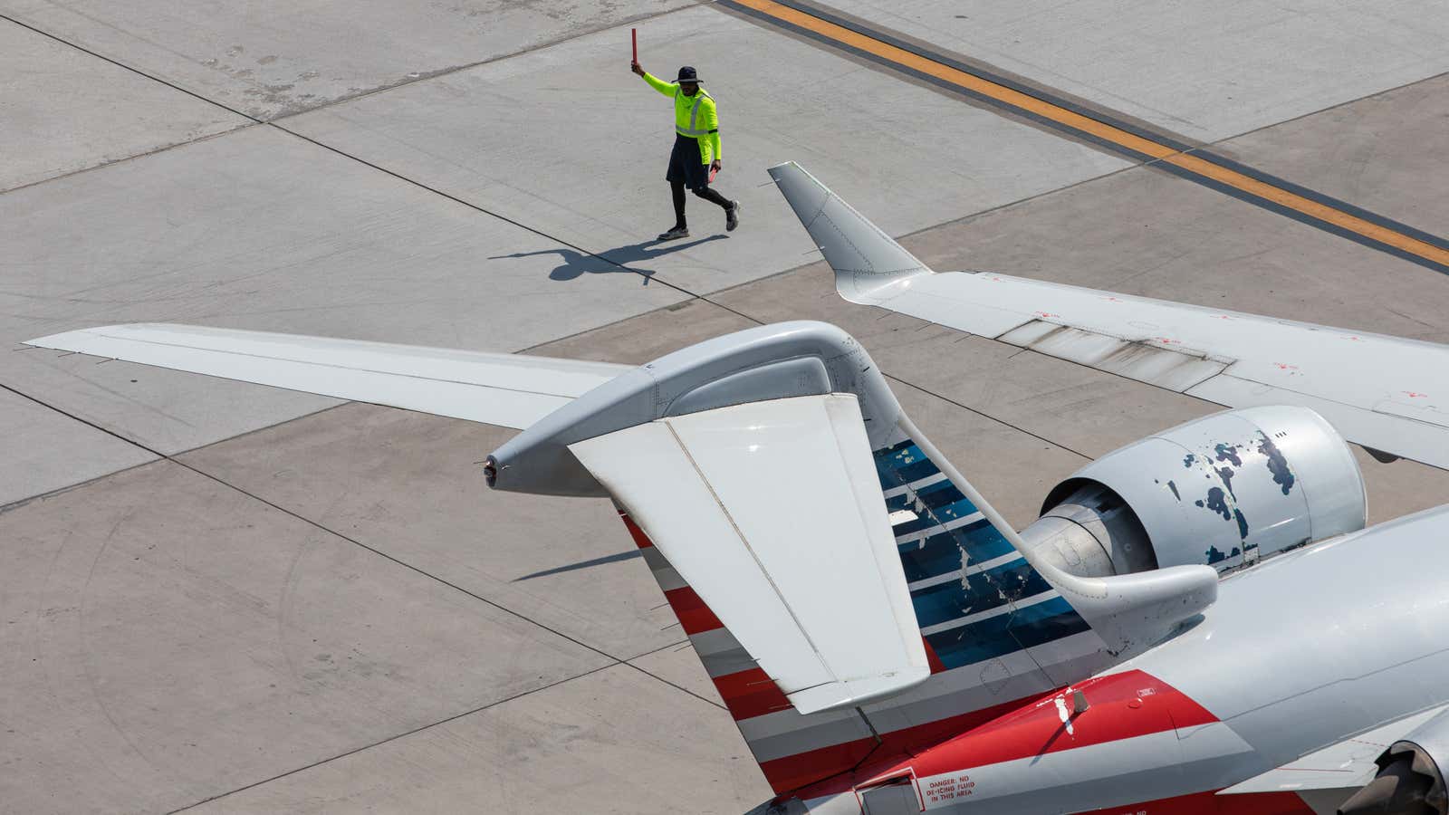 A man walks beside the tail of an airplane