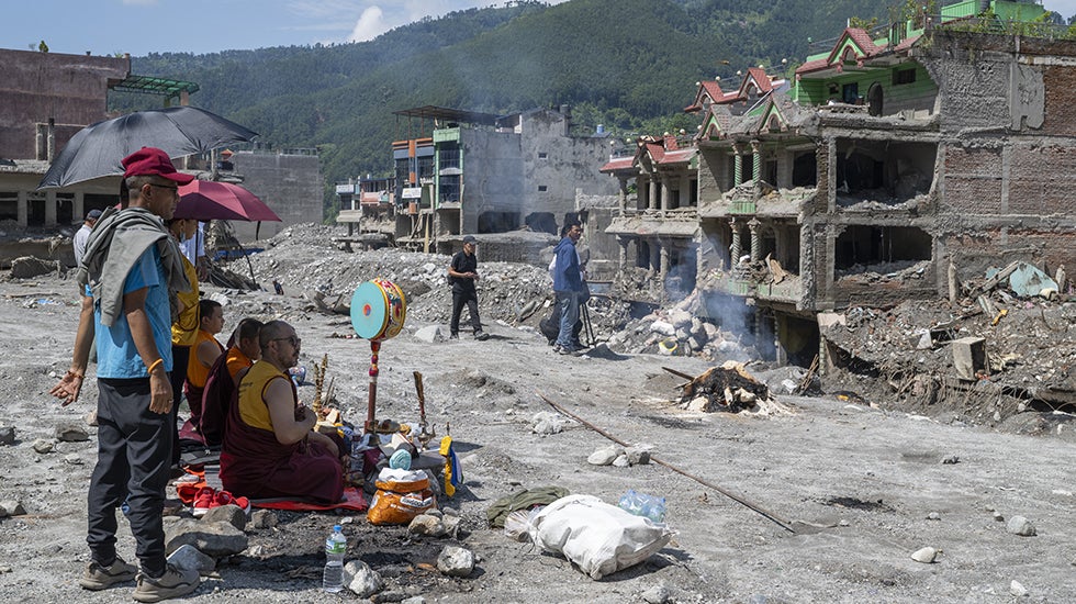 People gather to pray outside a flood destroyed building