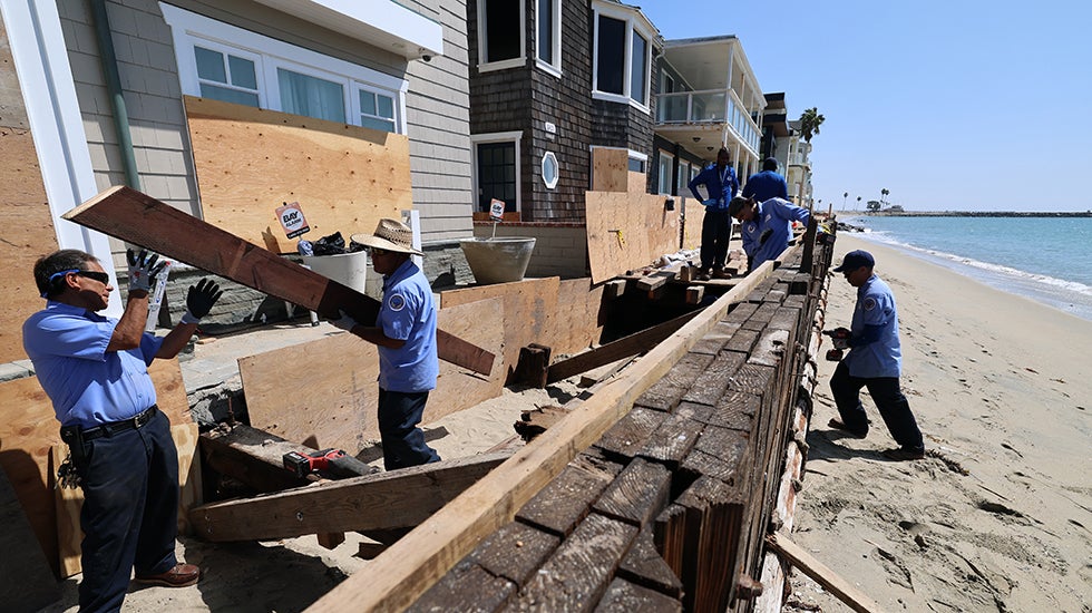 Workers work on a seawall on a beachfront
