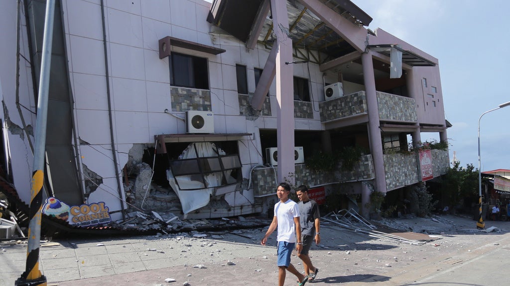 Residents pass by a collapsed structure after an earthquake in General Santos, Philippines on Monday, June 8, 2026. 