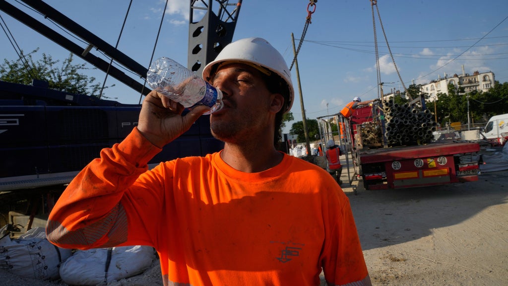 A construction worker drinks water to stay hydrated at a massive construction site as temperatures are expected to reach record highs in Paris, Wednesday, June 24, 2026. 