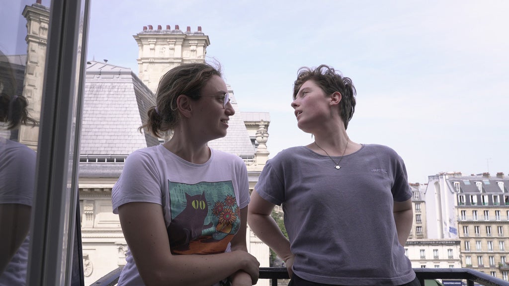 Two women stand on a balcony in Paris