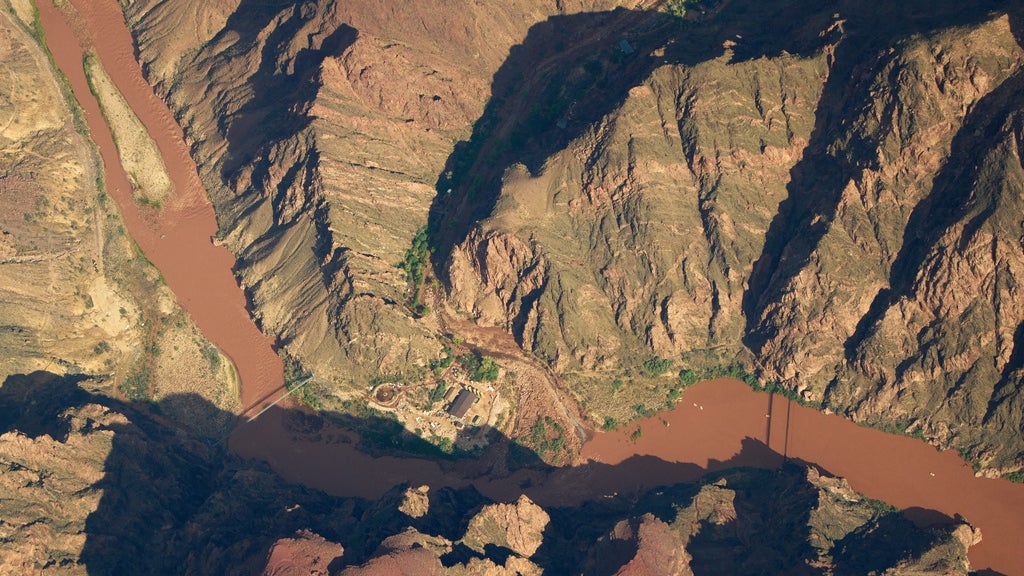 Aerial view of a muddy river confluence winding through a rugged desert canyon landscape.