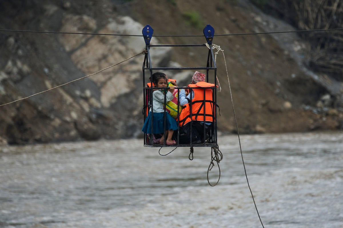 A young girl with her parents commute across the Trishuli river on a newly installed zipline