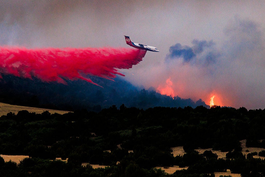 A firefighting plane drops fire retardant over the Aspen Acres fire on July 1, 2026 as over 35,000 acres and more than 100 structures have burned in Aspen Acres.