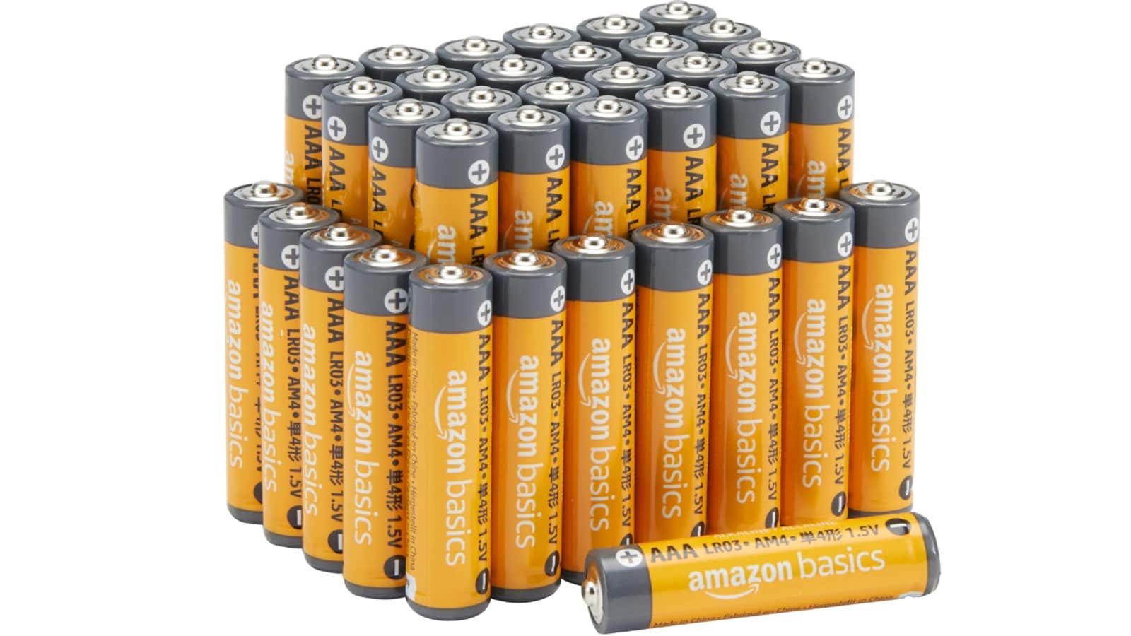 Large collection of orange and gray Amazon Basics AAA alkaline batteries arranged in multiple rows with one battery lying horizontally in front