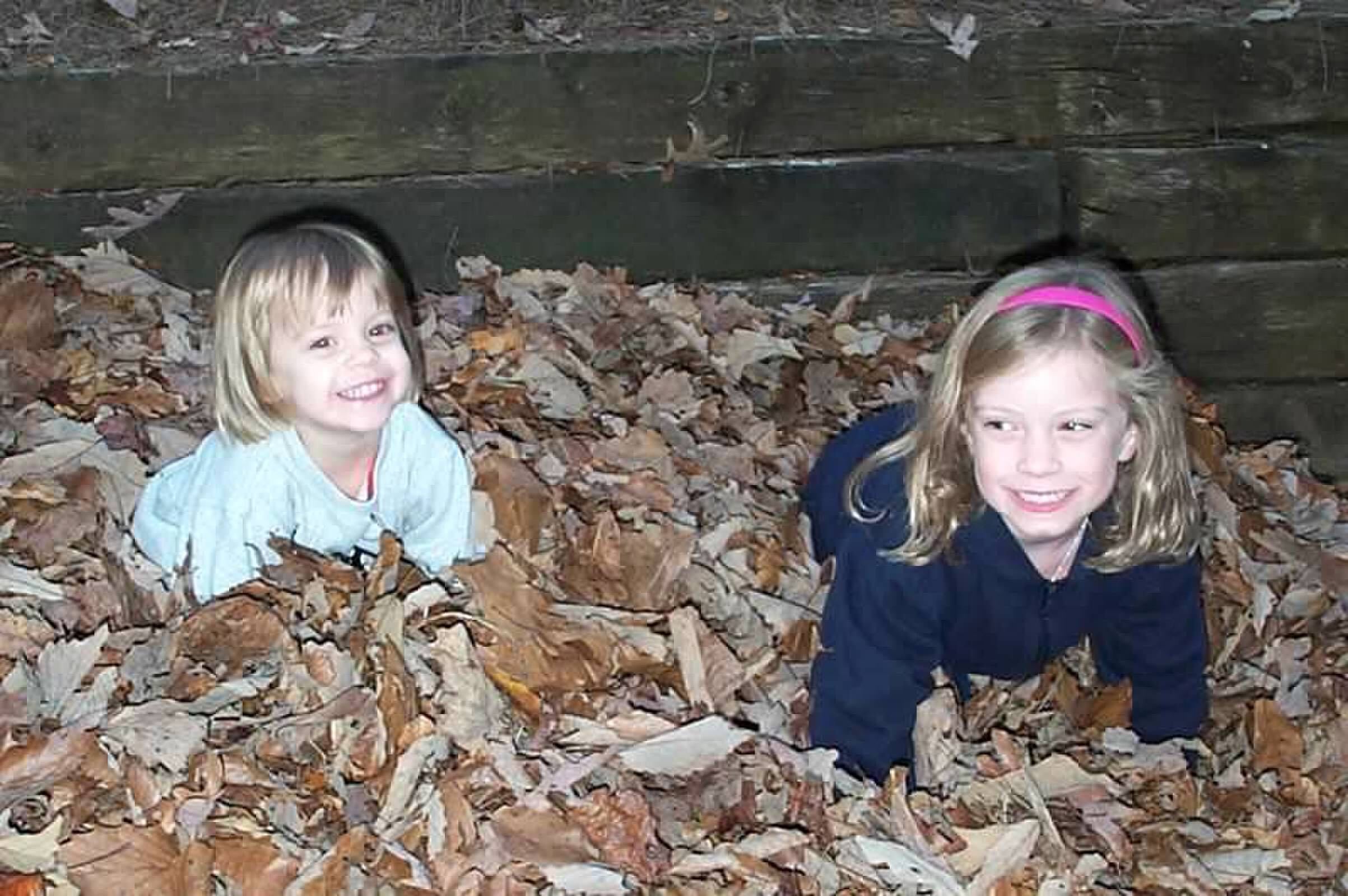 Meteorologist Caitlin Kaiser and her sister Megan Kaiser playing in a leaf pile in their backyard.