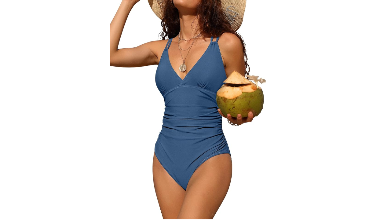 Woman in blue one-piece swimsuit and straw hat holding a coconut drink with a straw