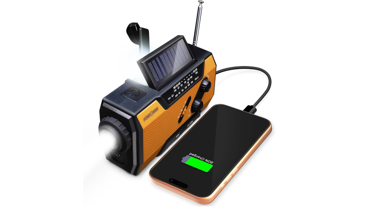 Orange and black emergency radio with solar panel, hand crank, flashlight, and antenna charging a smartphone via USB cable