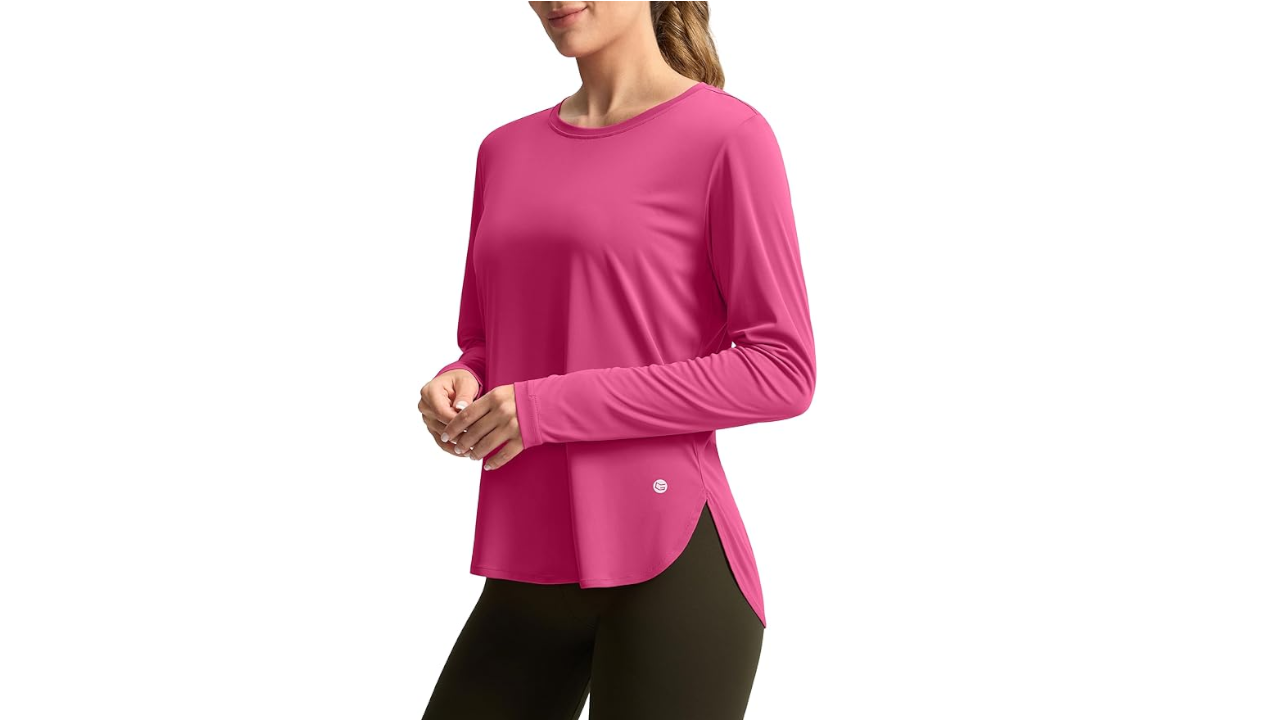 Woman wearing bright pink long-sleeved athletic top with side slits and dark leggings against white background