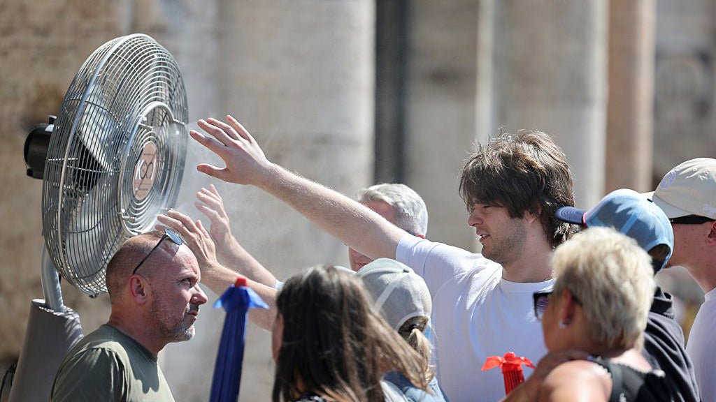 Tourists cool off beside an outdoor misting fan