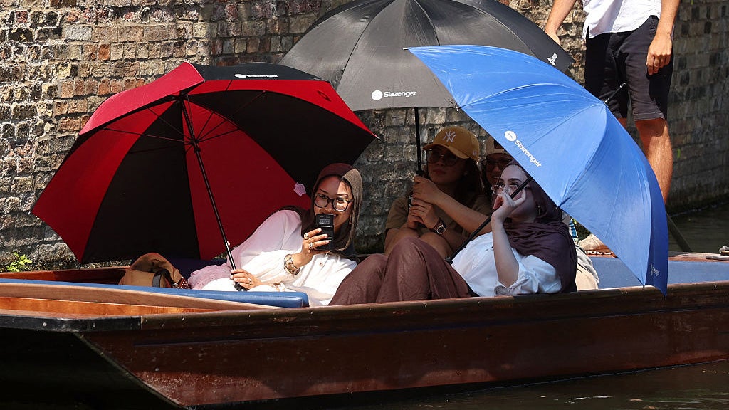 People sit under bright umbrellas as they take a boat ride.