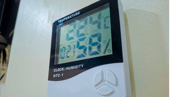 Digital HTC-1 thermometer showing temperature, humidity percentage, and clock display on a wall.