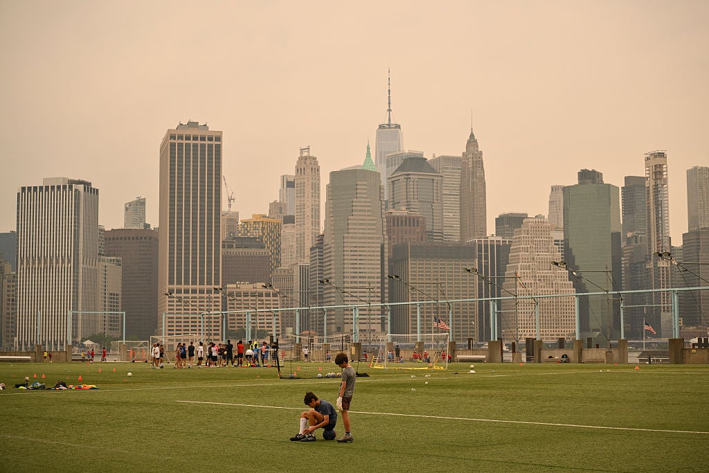 Kids play soccer in a field as thick smoke fills the skies of New York City from Canadian wildfires