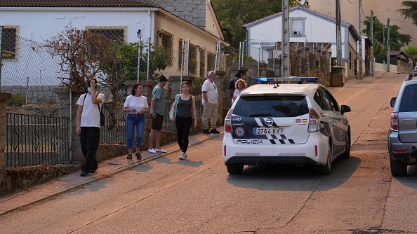 Police car parked on a steep street with several people standing on the sidewalk nearby
