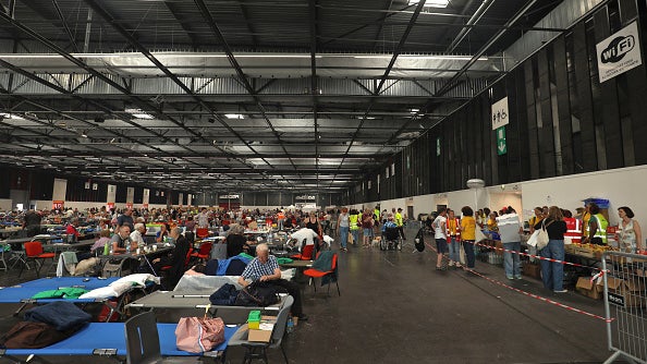 Large indoor hall with rows of tables, many people seated and standing, and a long line at booths on the right.