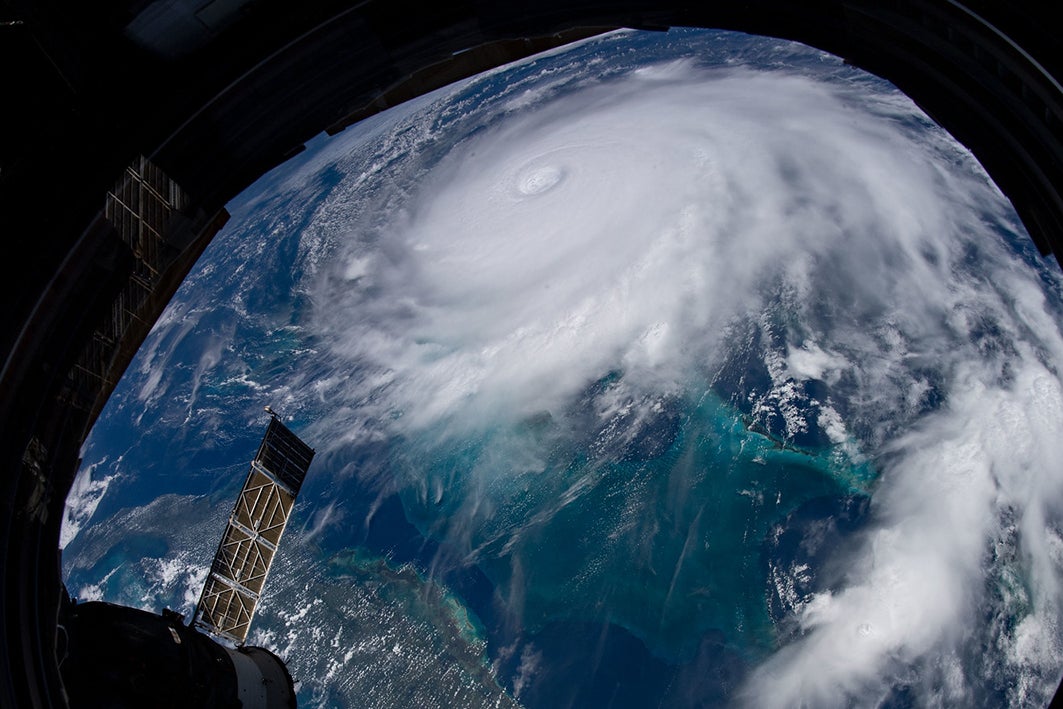 Hurricane seen from space above Earth with a satellite solar panel in the foreground