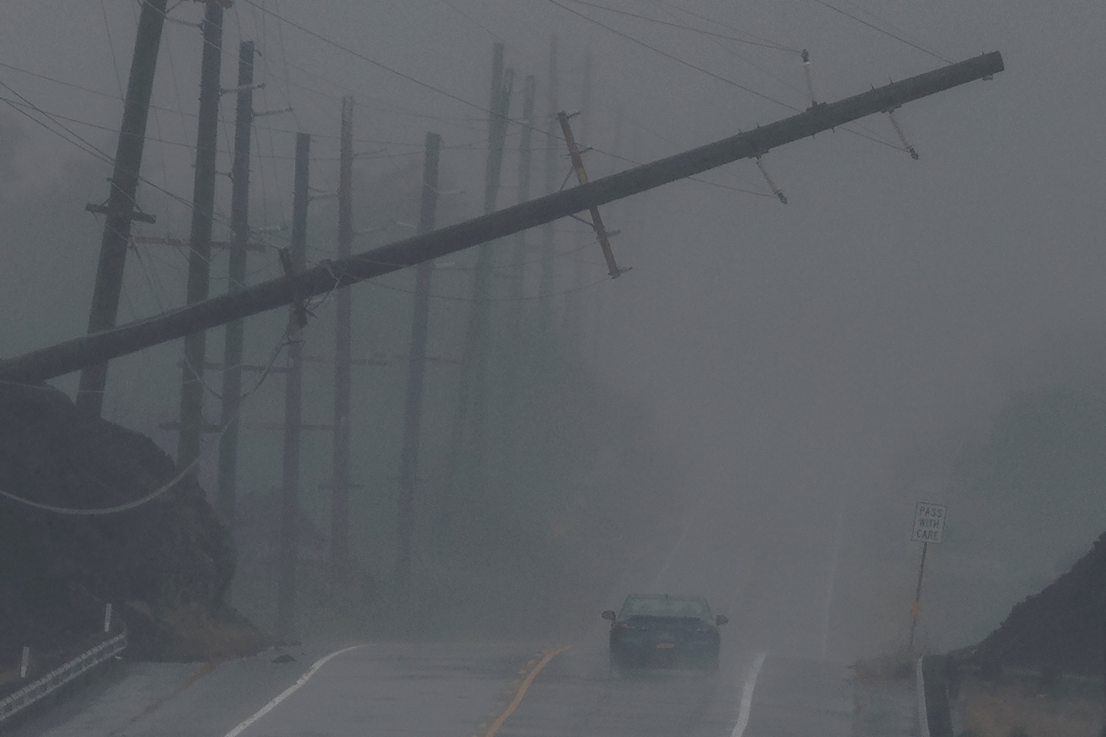 A vehicle approaches a downed utility pole dangling above Mamalahoa Highway during Hurricane Lala near Ocean View, Hawaii, Saturday, Aug. 15, 2026. The tropical storm strengthened into a hurricane as it approached Hawaii. 