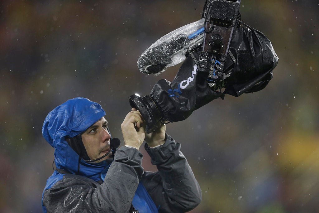 man wipes camera lens in rain