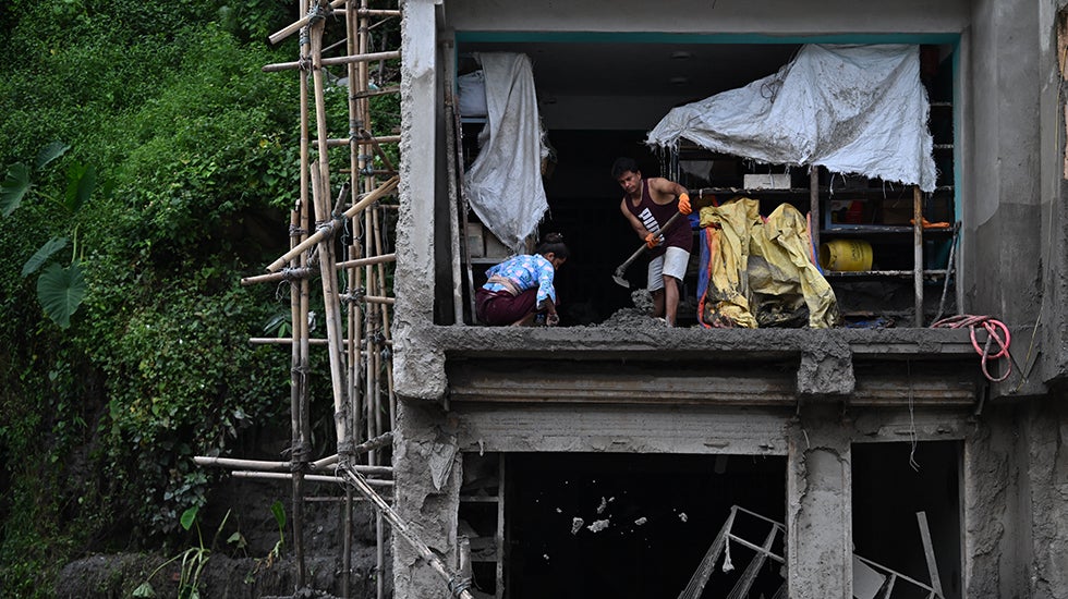 Two people work to clean in a building where the wall was ripped off
