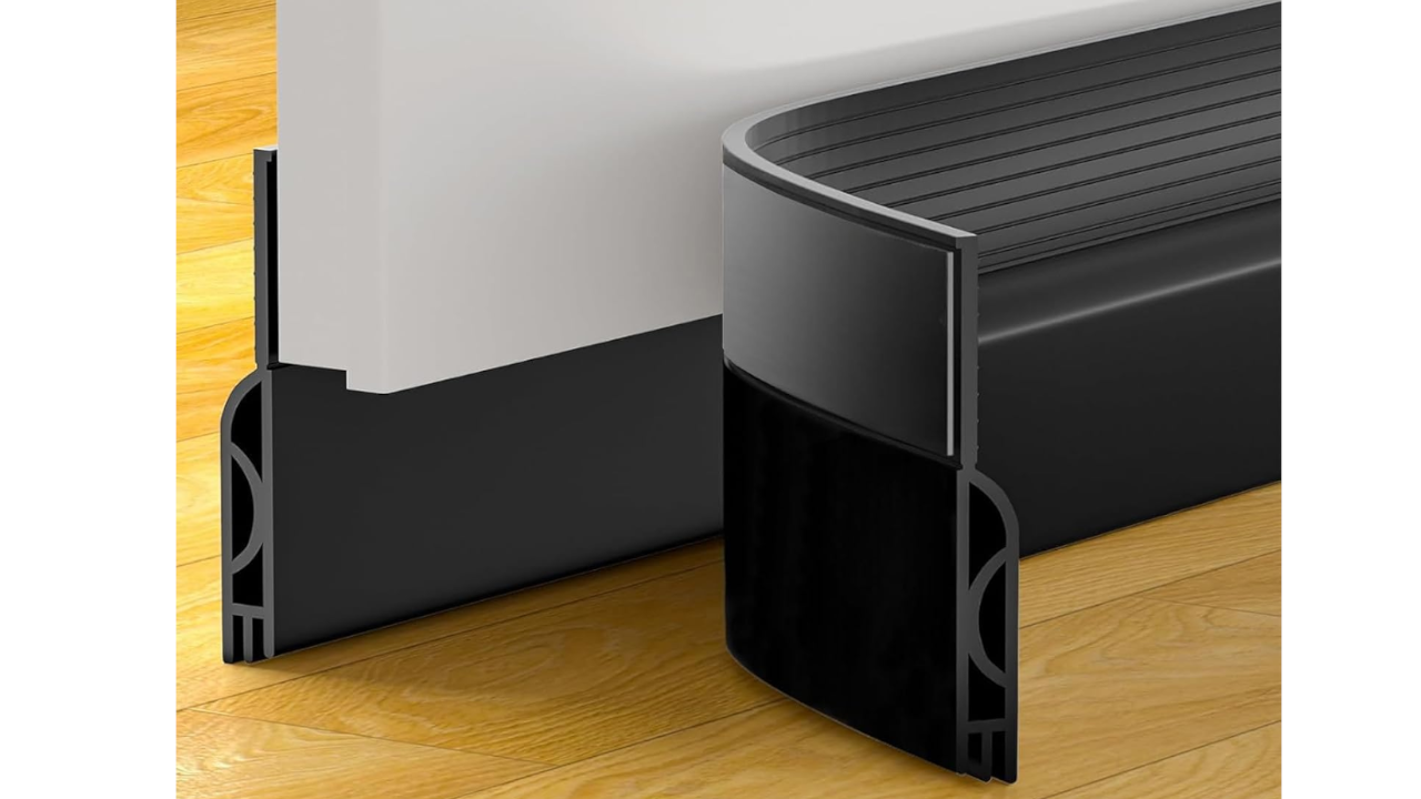 Black rubber door bottom sweep seal attached to a white door on a wood floor