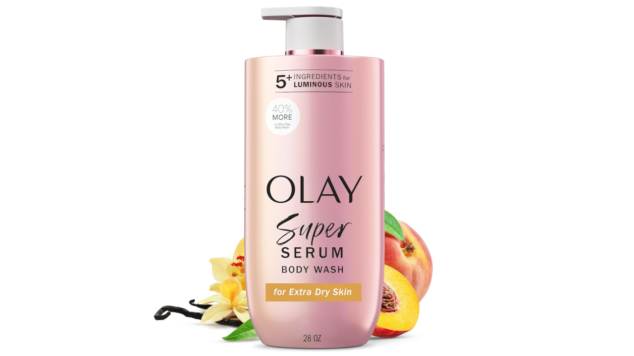 Pink pump bottle of Olay Super Serum Body Wash for extra dry skin, with peach and vanilla flower beside it