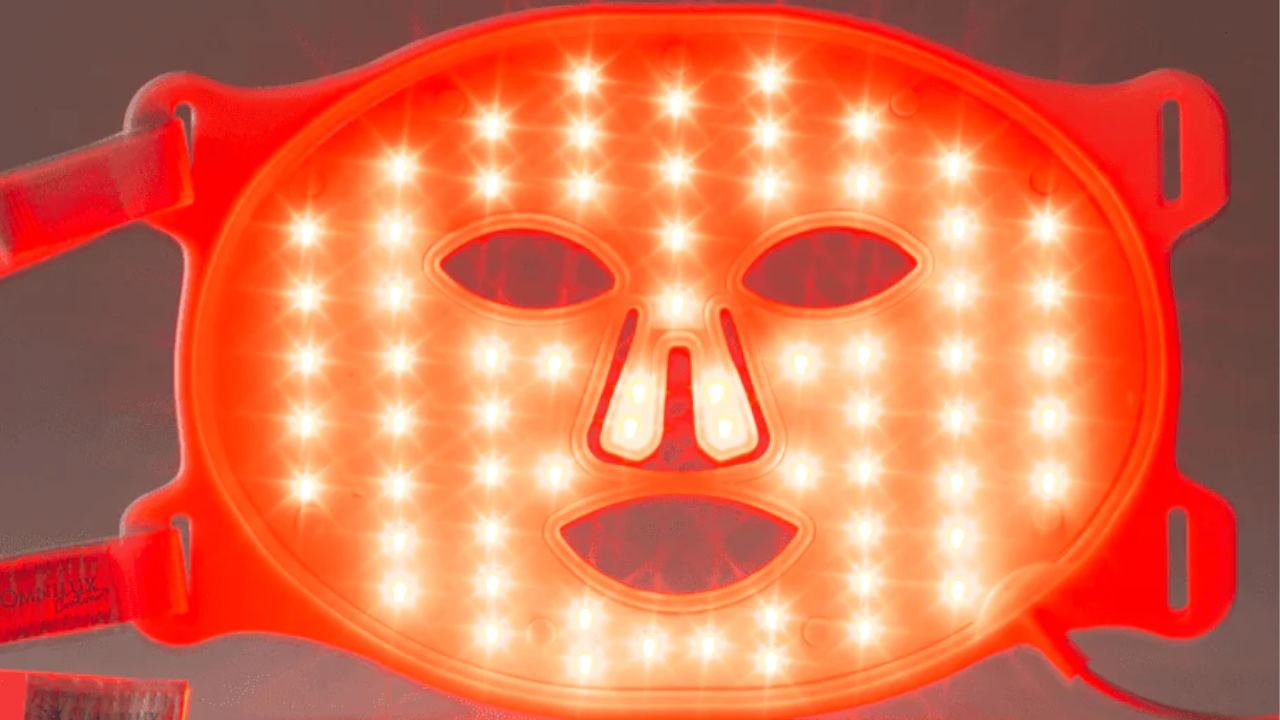 Red LED light therapy face mask with multiple bright lights arranged across facial features and adjustable straps