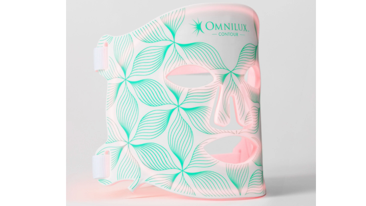Omnilux Contour LED light therapy mask with white base and green tropical leaf pattern design against gray background
