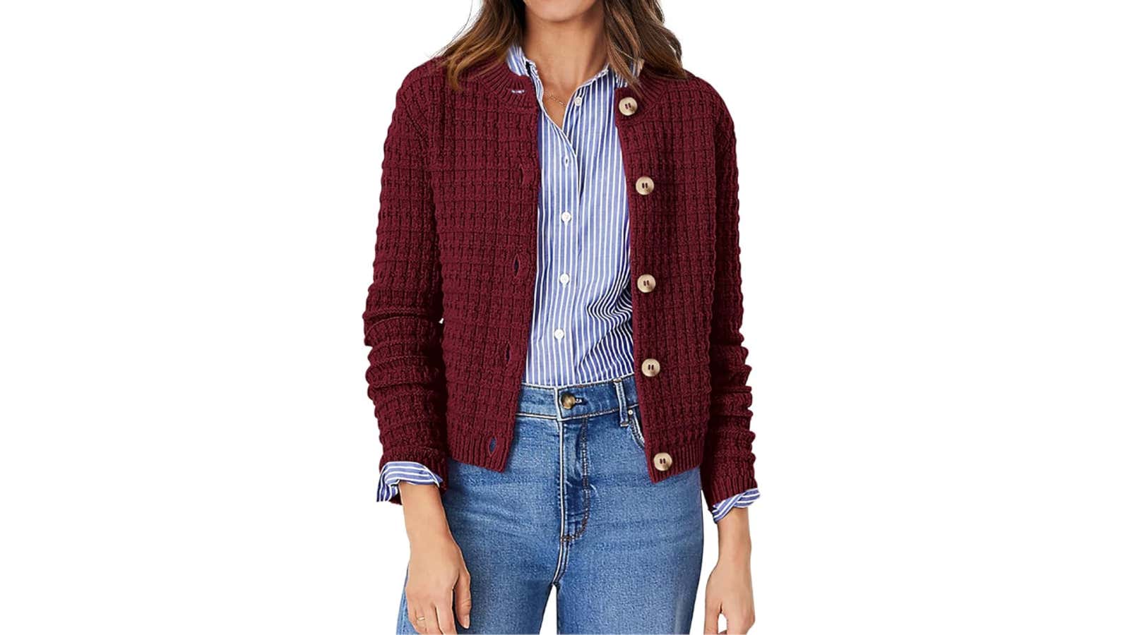 Woman wearing a maroon knit button-up cardigan over a blue striped shirt with blue jeans