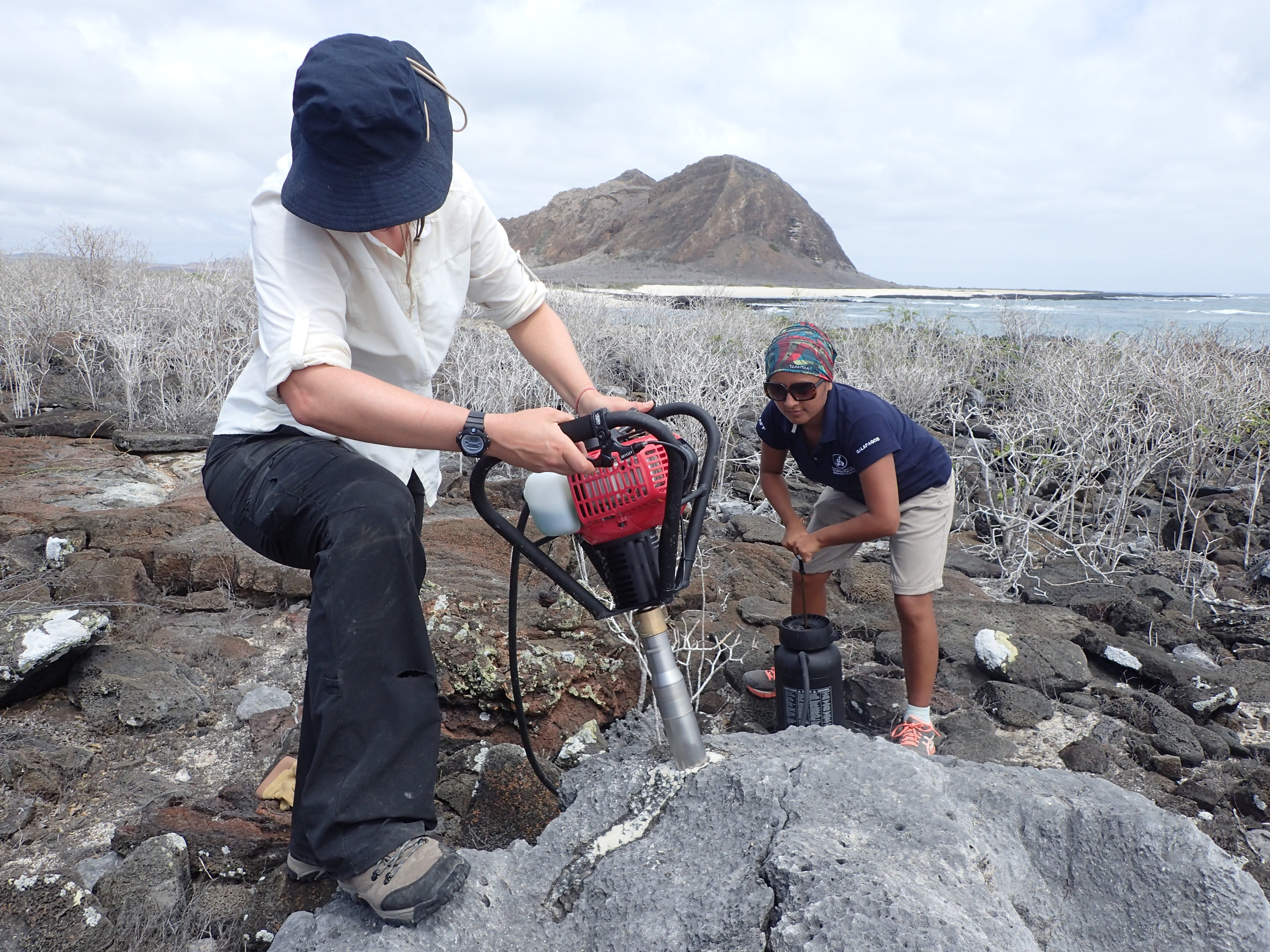 University of Arizona researcher Diane Thompson takes a sample from an ancient coral, along with Andrea Lema formerly of Charles Darwin Research Station.