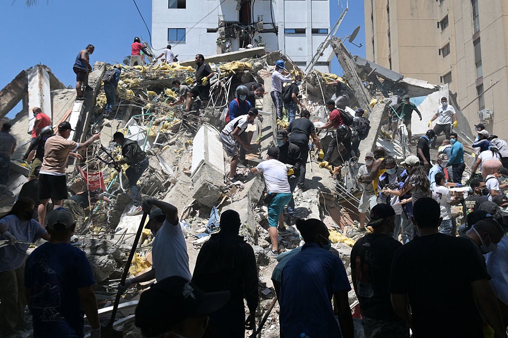 Crowds of rescue workers and volunteers search through collapsed building rubble after a disaster