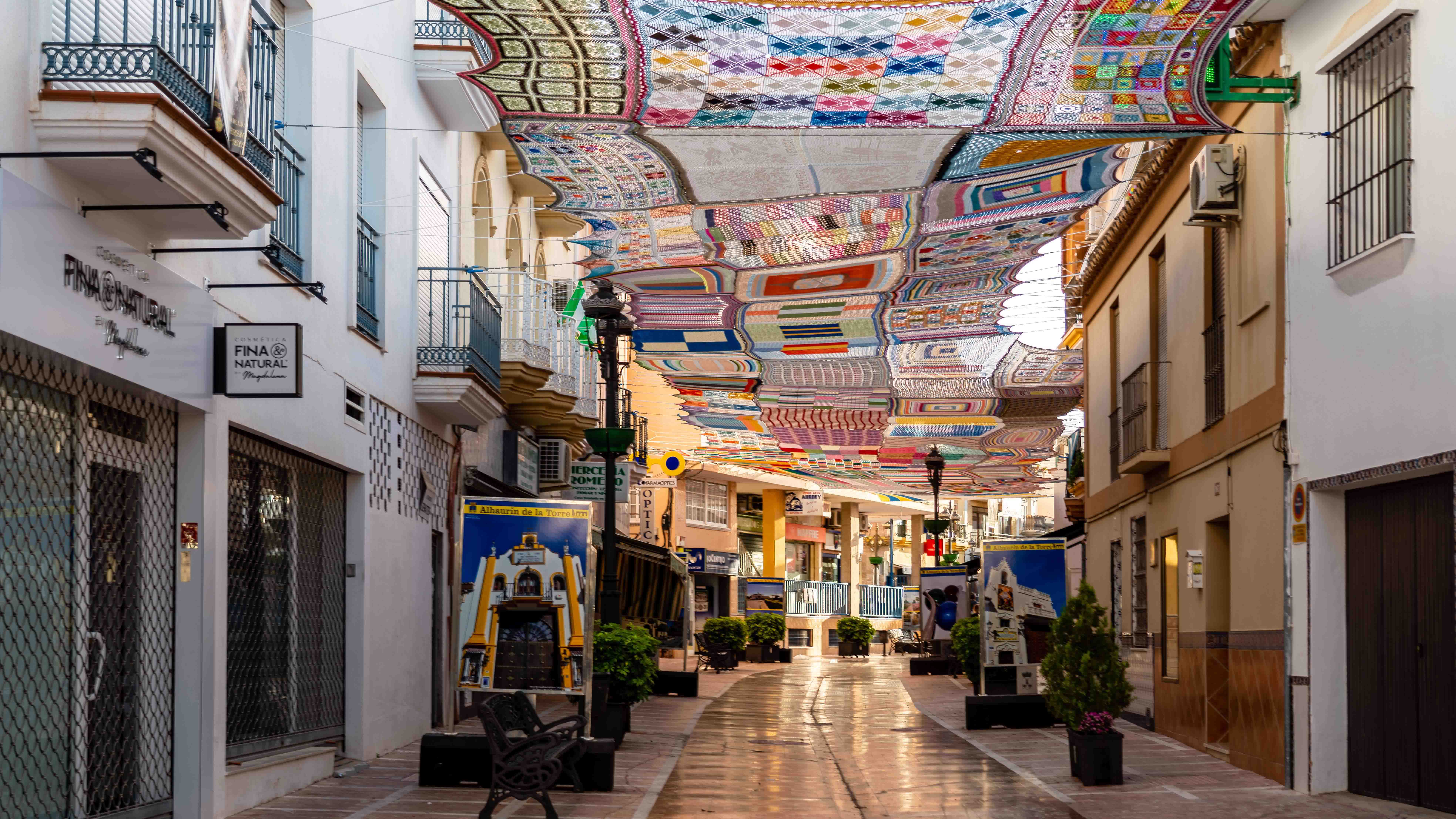 Colorful crocheted textiles hang overhead in a pedestrian shopping street in Alhaur&iacute;n de la Torre, Spain