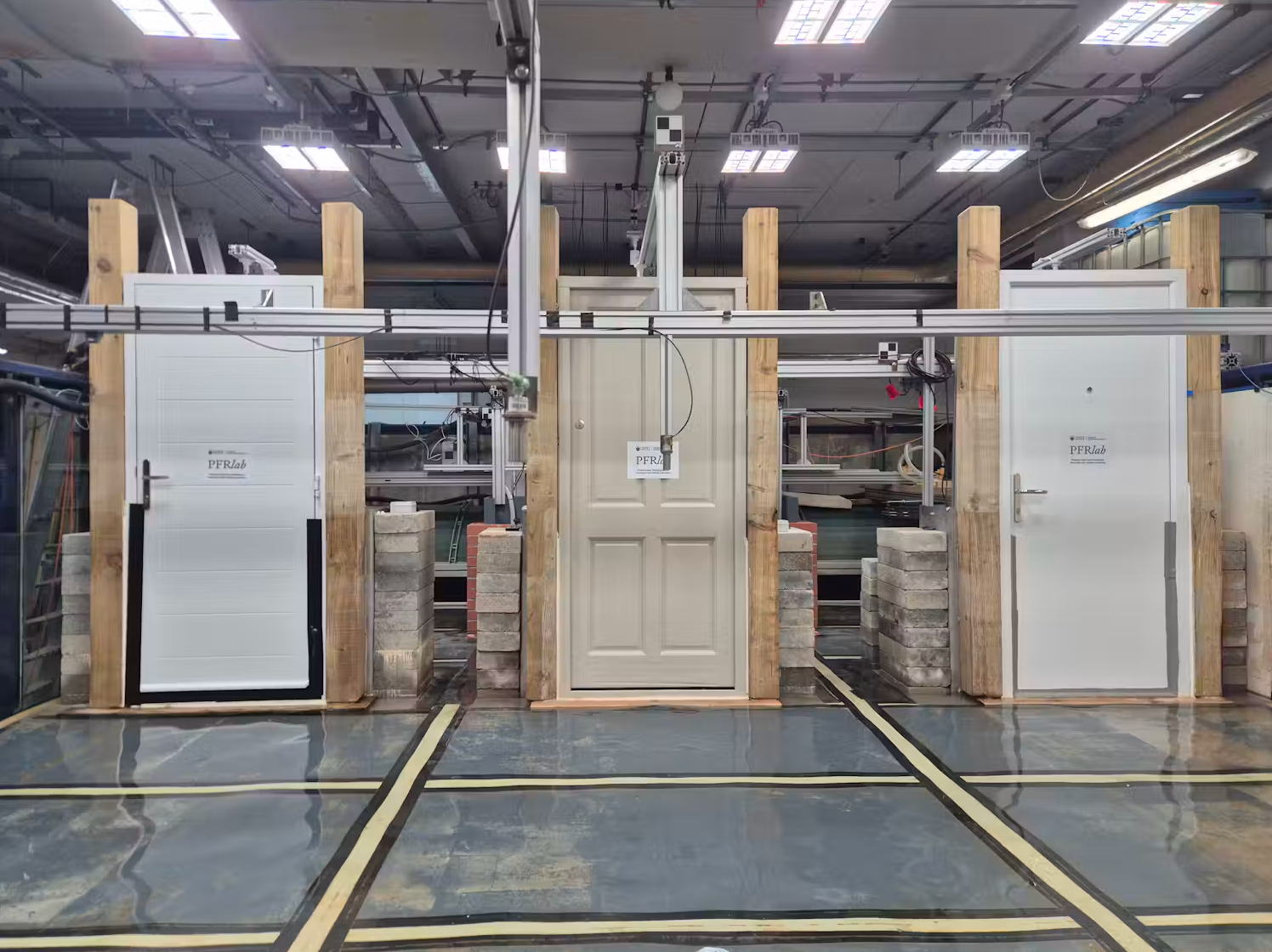 Three test doors labeled PFRlab mounted in wooden frames with concrete block supports in an industrial testing facility