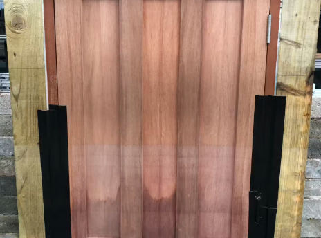 Wooden paneled door with vertical wood grain, flanked by black trim and timber posts