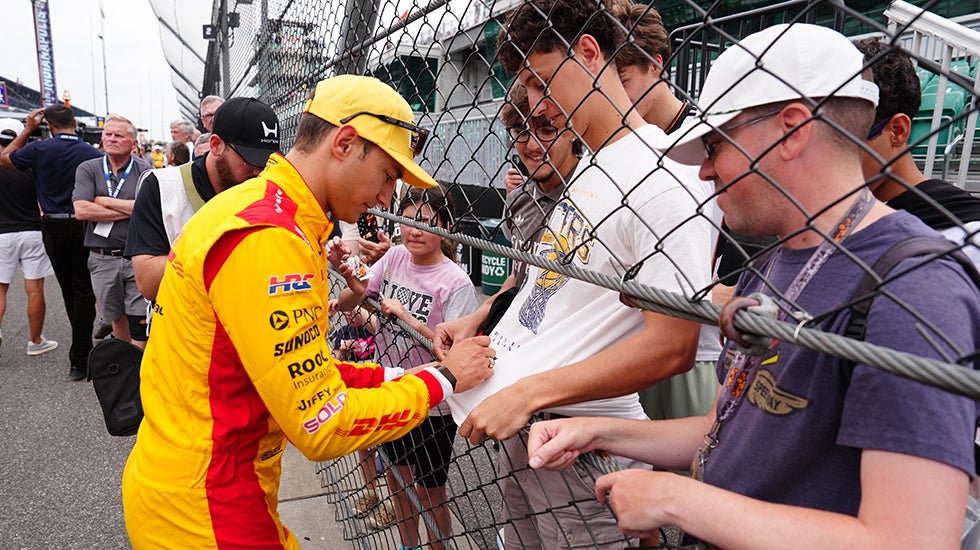 An Indy race car driver signs autographs